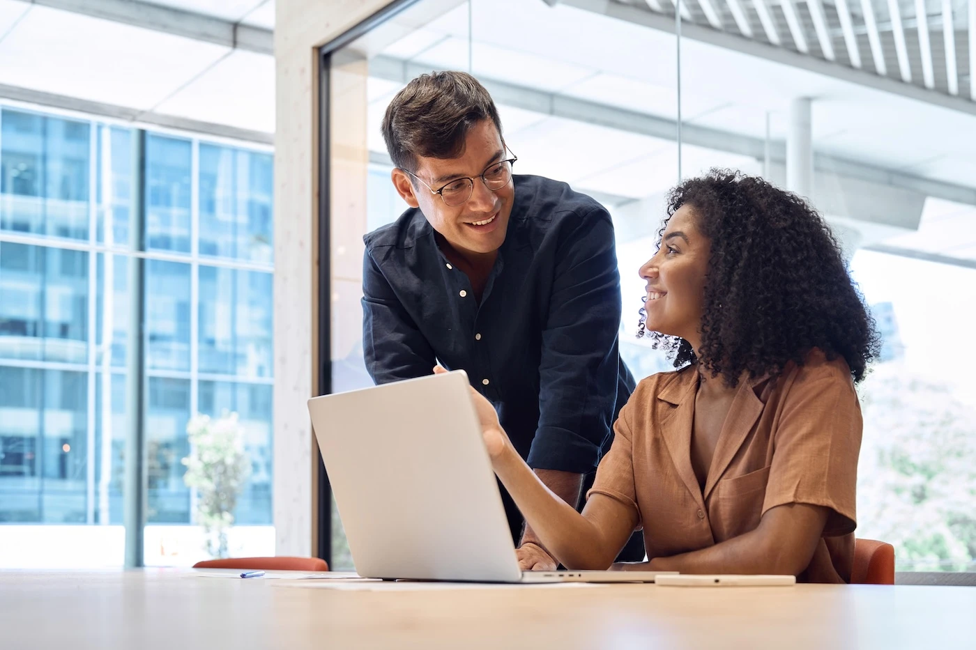Two diverse business professionals collaborating on cybersecurity solutions using a laptop in an office, representing expert Cybersecurity Services Kalamazoo MI.